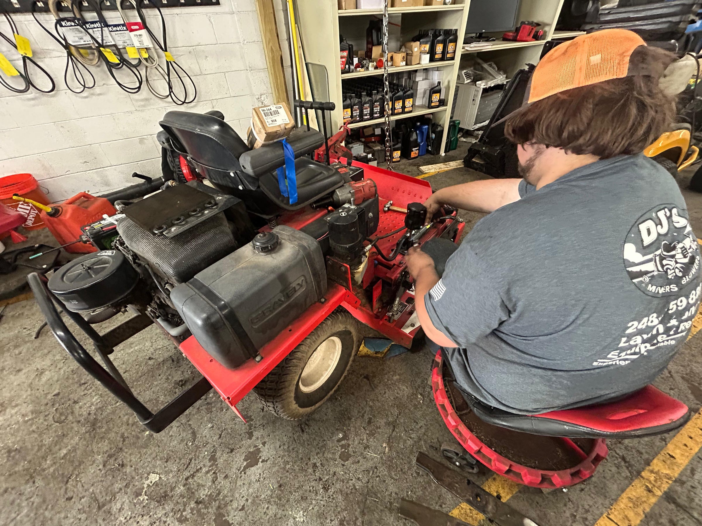 Person working on a red lawn mower in a workshop setting